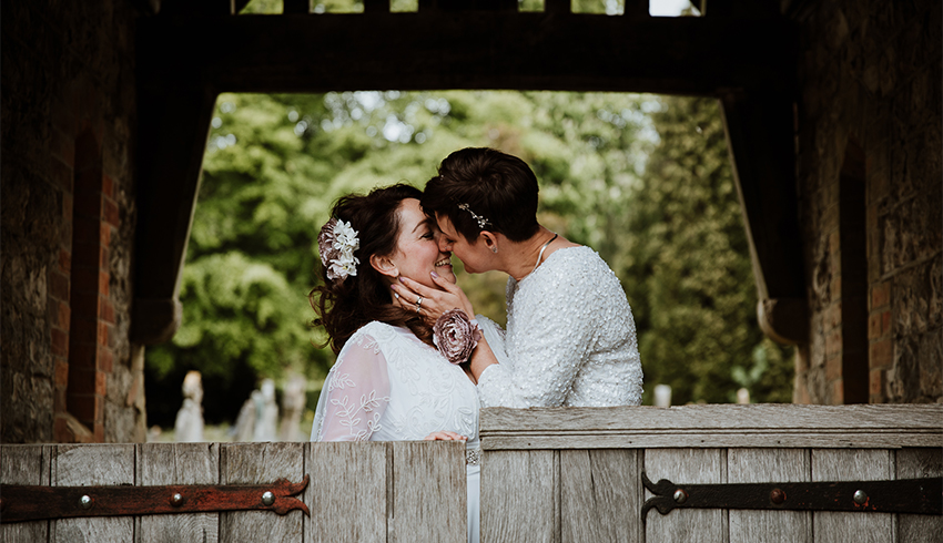 Just married, wedding couple kissing under archway, image by Nicola Dawson Photography