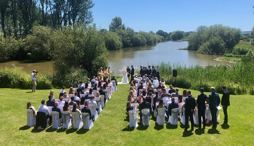Outdoor wedding ceremony with stunning views in the background of the lake at the Milwards Estate