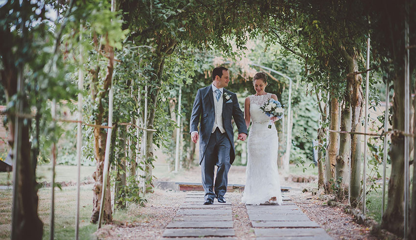 Wedding couple walking through the wedding arch at Rowhill Grange
