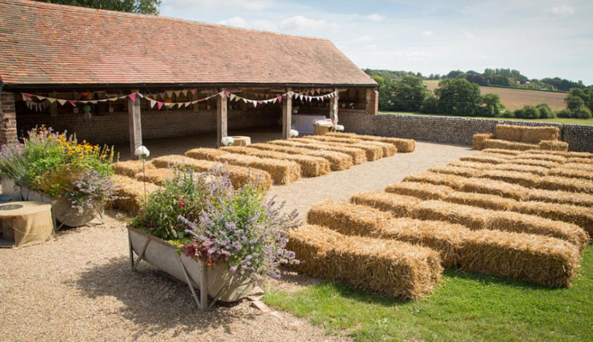 The outside wedding ceremony venue at the Sussex Barn, set up with haystacks for the wedding guests to sit on